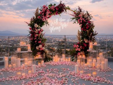 Romantic floral proposal setup with candles and a 'Will You Marry Me?' sign.