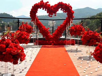 Red floral heart-shaped proposal setting with "Will you marry me?" sign.