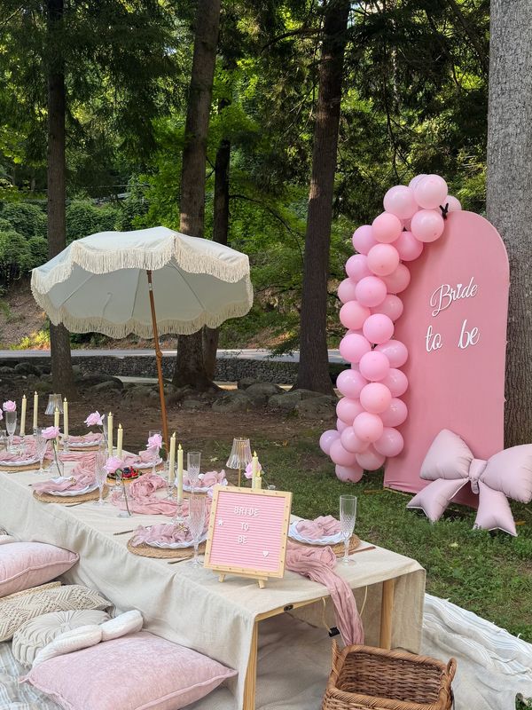 Outdoor bridal shower setup with pink decorations and balloons.