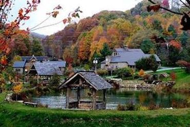 Cozy lakeside cottages surrounded by colorful autumn trees and hills.