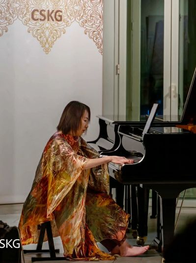 Woman playing piano barefoot in colorful dress.