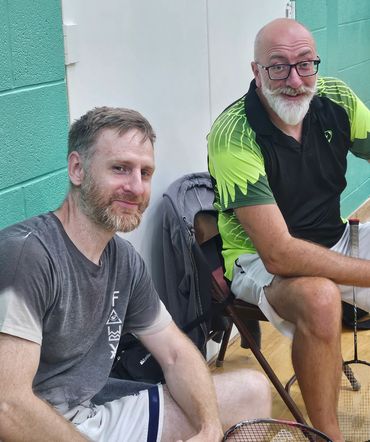 Two men relaxing on chairs after badminton.
