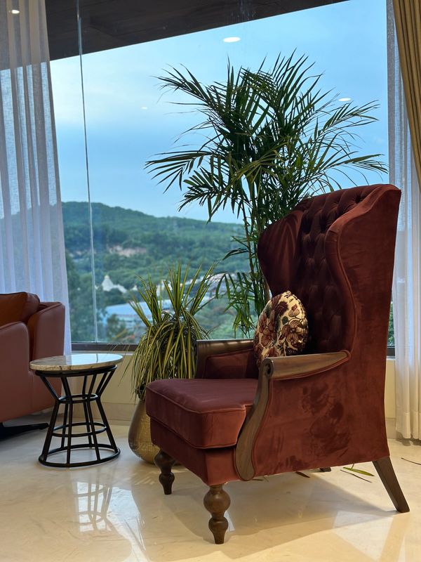 Cozy corner with a plush armchair, side table, and indoor plants by a large window.