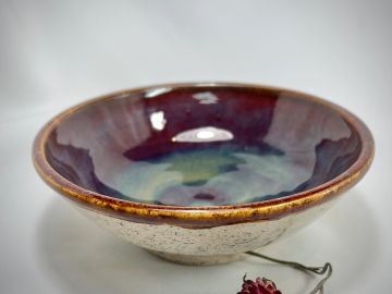 A handcrafted ceramic bowl with a glossy, multicolored glaze.