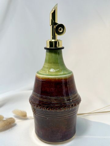 Ceramic olive oil dispenser with glossy green and brown glaze and a gold-tone spout.