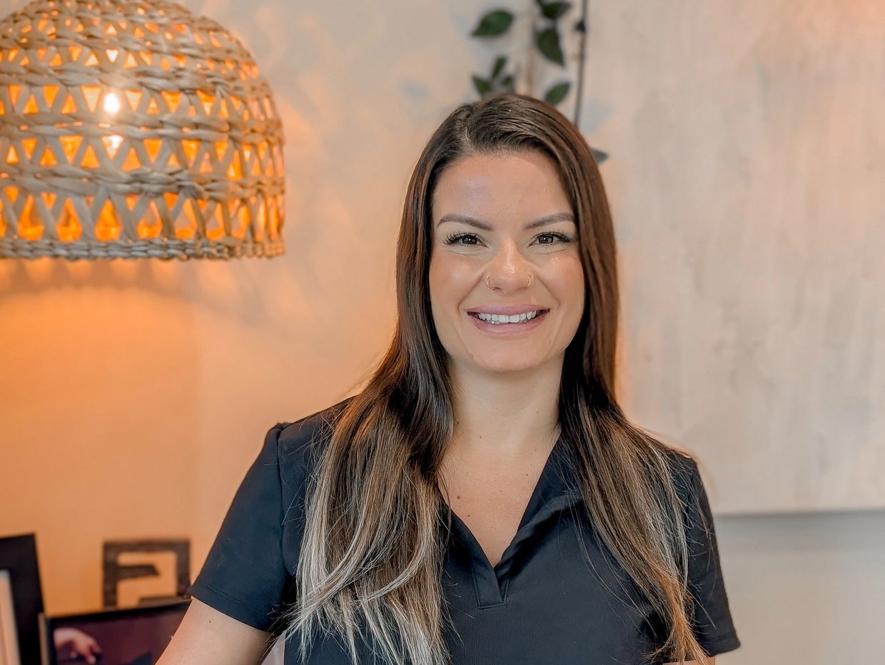 Smiling woman with long hair and nose rings.