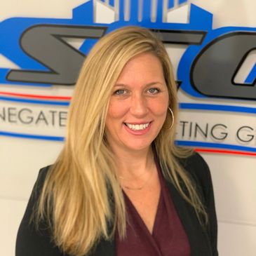 Smiling woman with long blonde hair in front of a company logo.