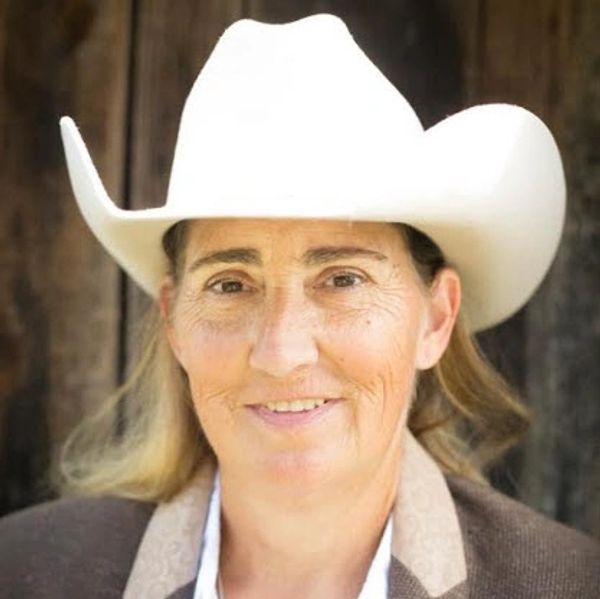 Woman wearing a white cowboy hat and smiling.