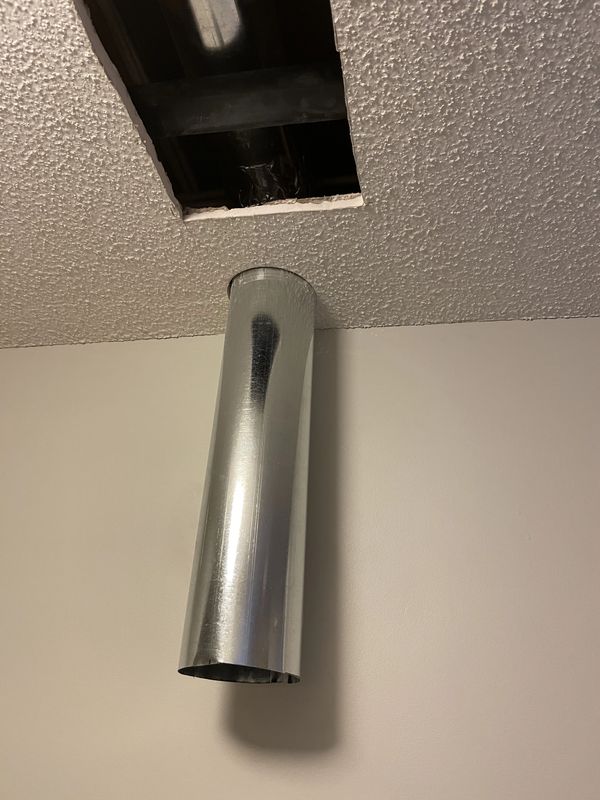 Metal duct hanging from ceiling with open vent.