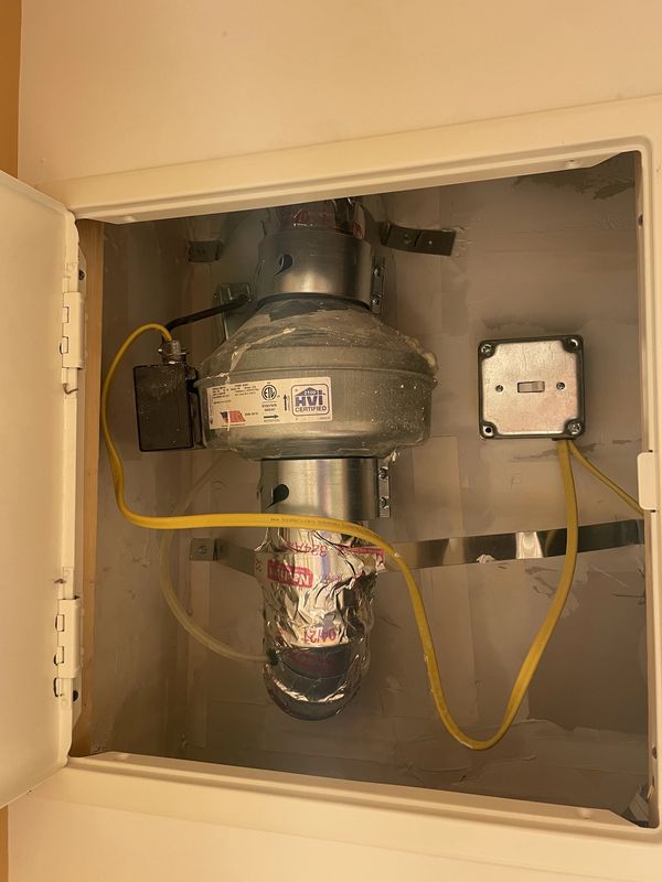 Exhaust fan with electrical wiring inside a cabinet.