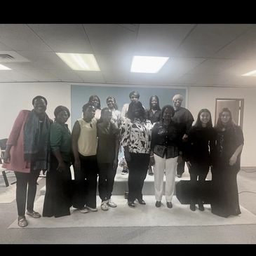 Group of diverse women standing together indoors, smiling for a photo.