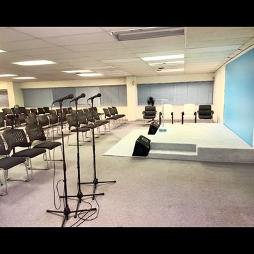 Empty conference room with a small stage and microphones set up.