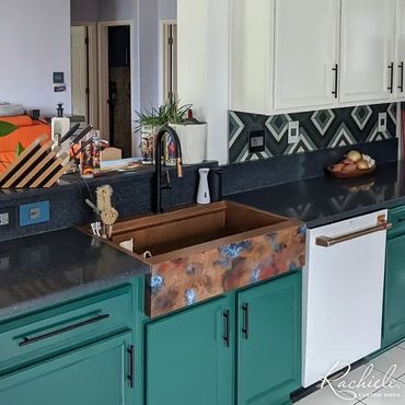 copper retrofit farmhouse sink with a color patina in a kitchen with blue cabinets and black faucet