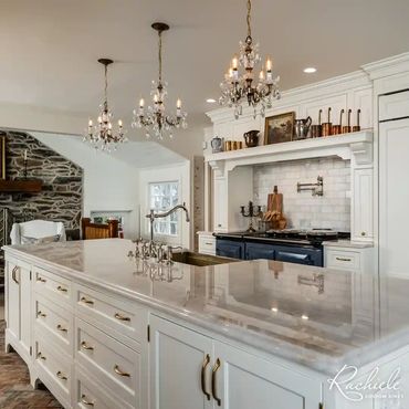French country kitchen in Virginia with white cabinets, a brass farmhouse sink and brass hardware