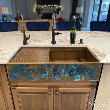 36" custom copper farmhouse sink by Rachiele with a patina with rich blue accents in a marble top