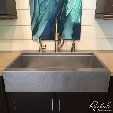 A top mounted stainless farmhouse sink with a hammered apron replaced a concrete kitchen sink.