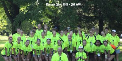 Group photo of summer camp participants wearing bright yellow shirts outdoors.
