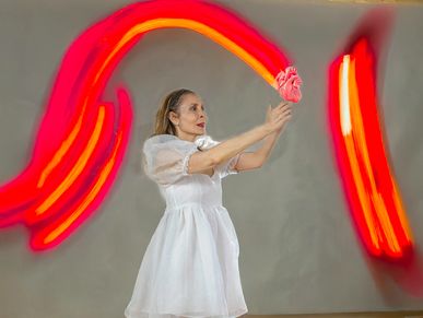 Woman in a white dress appears to hold a glowing heart with red light trails.