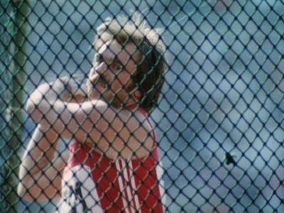 Track athlete preparing to throw a discus behind a fence.