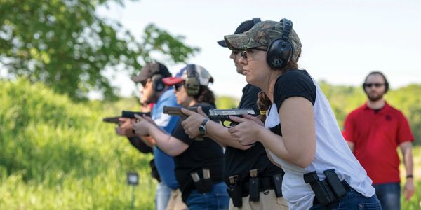 Group of people practicing shooting at an outdoor gun range.
