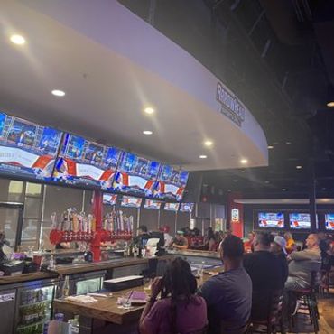 Patrons watching the game, crowd gathered by the huge tv screens at Arrowhead Sports Plano