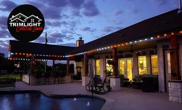 LED Trimlights are seen in orange in white next to a residential pool in a backyard.
