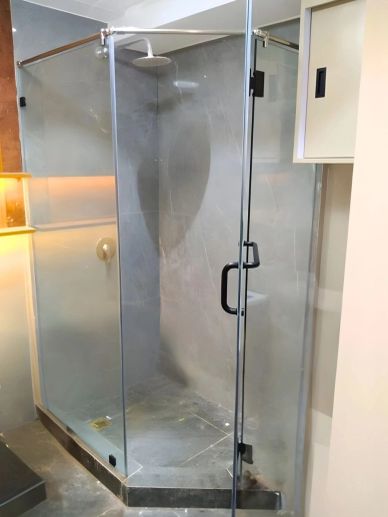 Modern glass shower enclosure with a rain showerhead and grey tiles.