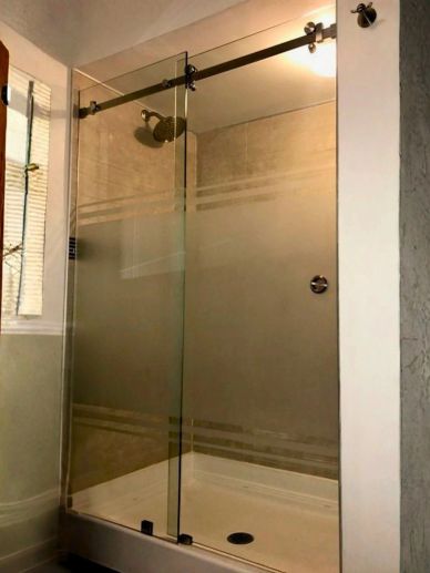 Modern glass shower enclosure with a sliding door and frosted design.