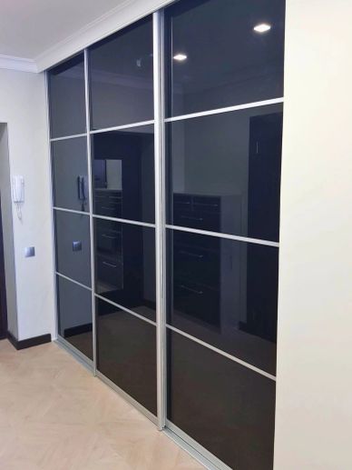 Modern wardrobe with black sliding doors and silver frames in a bright room.