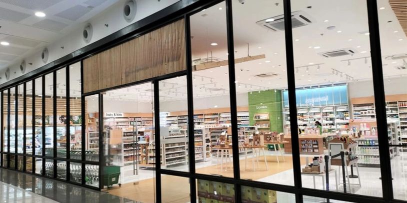 Modern retail store with glass walls showcasing organized shelves and products.