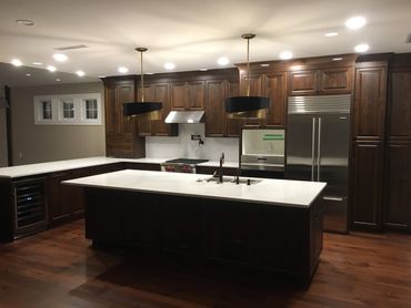 Modern kitchen with dark wood cabinets and white countertops.