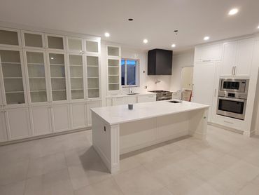 Modern white kitchen with large island and built-in appliances.