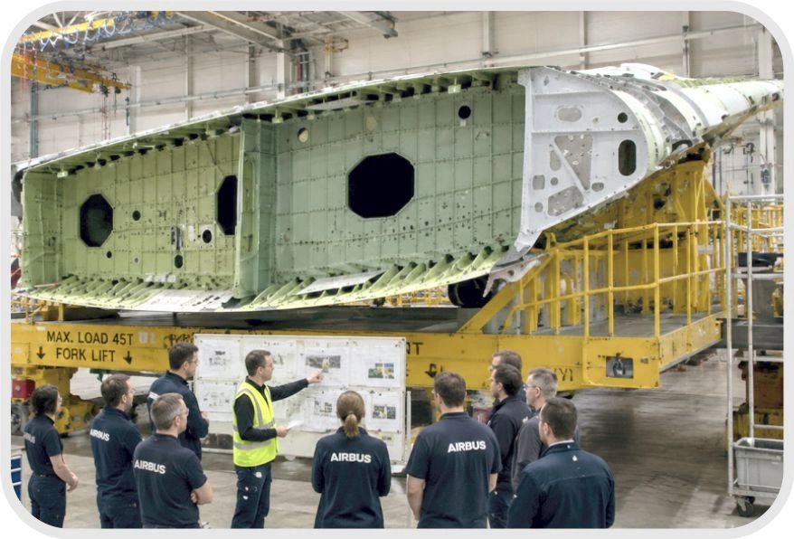 Airbus team discussing an aircraft wing section inside a factory.