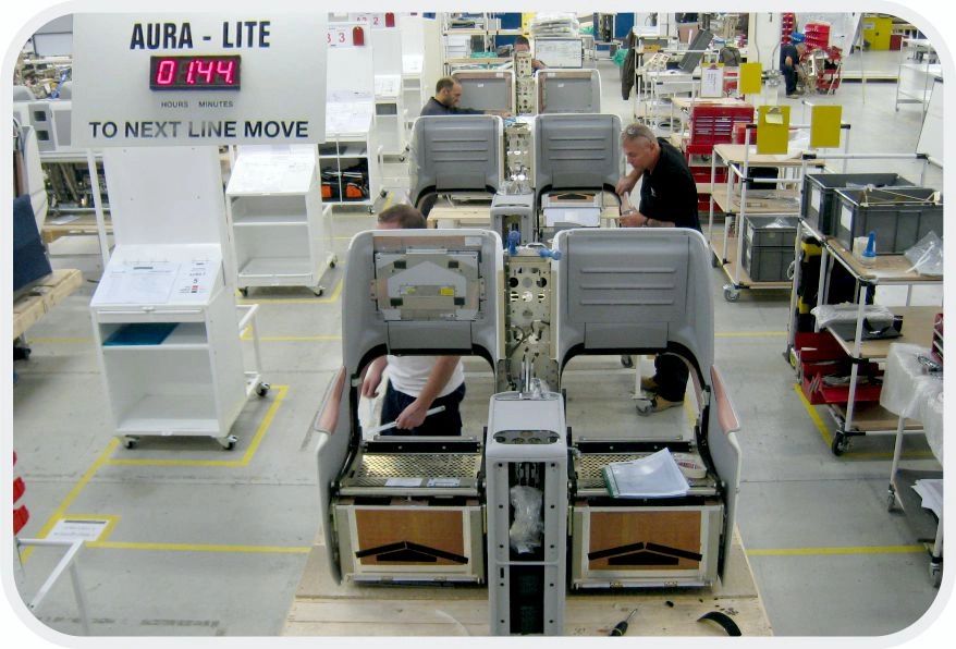Workers assembling aircraft seats in a factory.