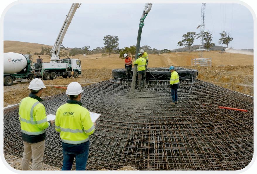 Construction workers pouring concrete over rebar framework.