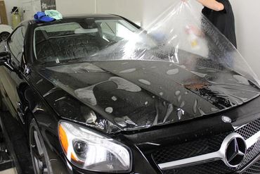 Picture of a clear bra ppf paint protection being installed on a full hood of Mercedes at Tint Pros
