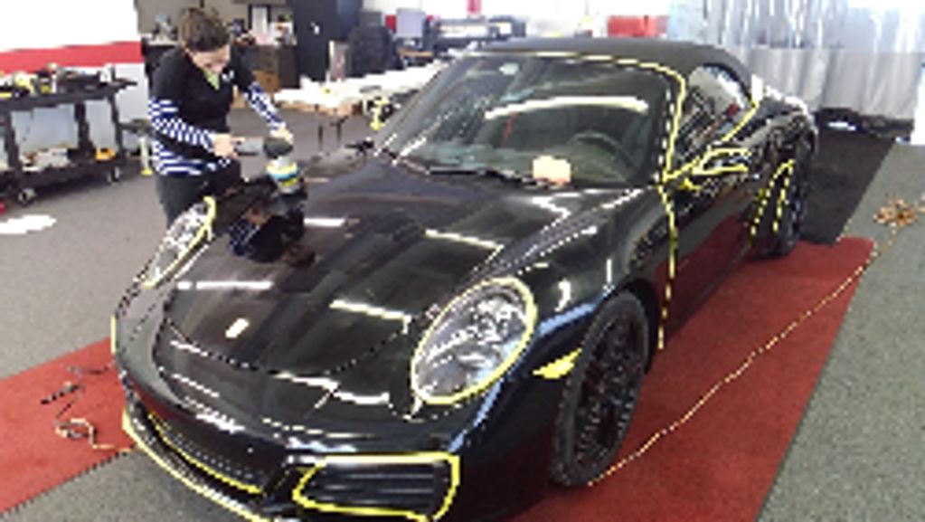 black Porsche 911 car  taped off and being buffed and paint correction being done