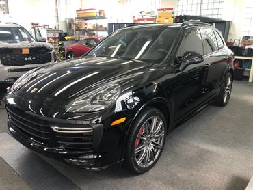 Black Porsche Ceramic Coated sitting inside Tint Pros Cleveland building next to Lexus LC 500