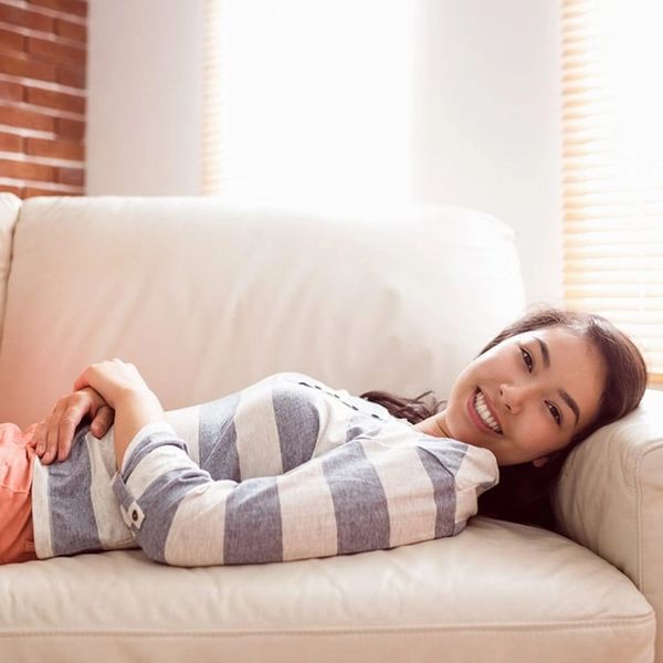 Smiling woman lying on sofa.