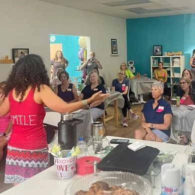 A woman speaks to an attentive audience in a colorful room.