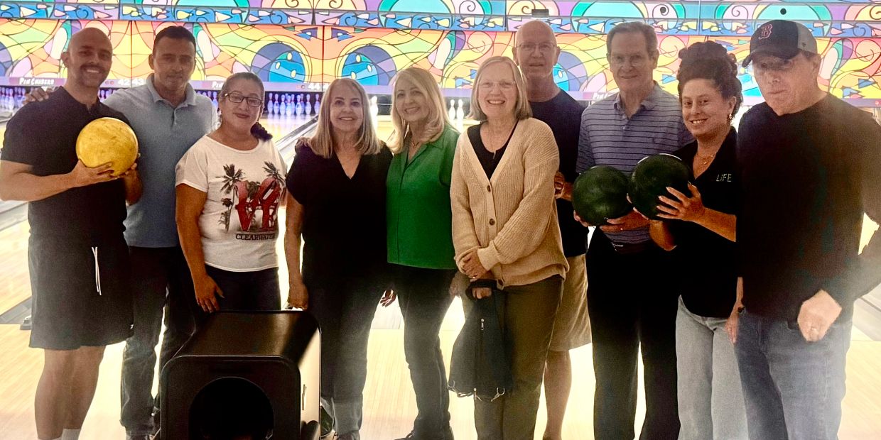 Group of people at a bowling alley holding bowling balls.