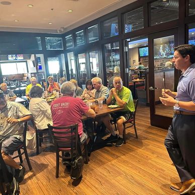 A group of people gathered around a table in a restaurant, engaged in conversation.