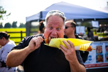 a middle aged man taking a bite into a potato swirl in Moorpark, CA at Crave Night Market