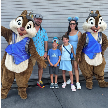 Family posing with Chip and Dale characters at a theme park.