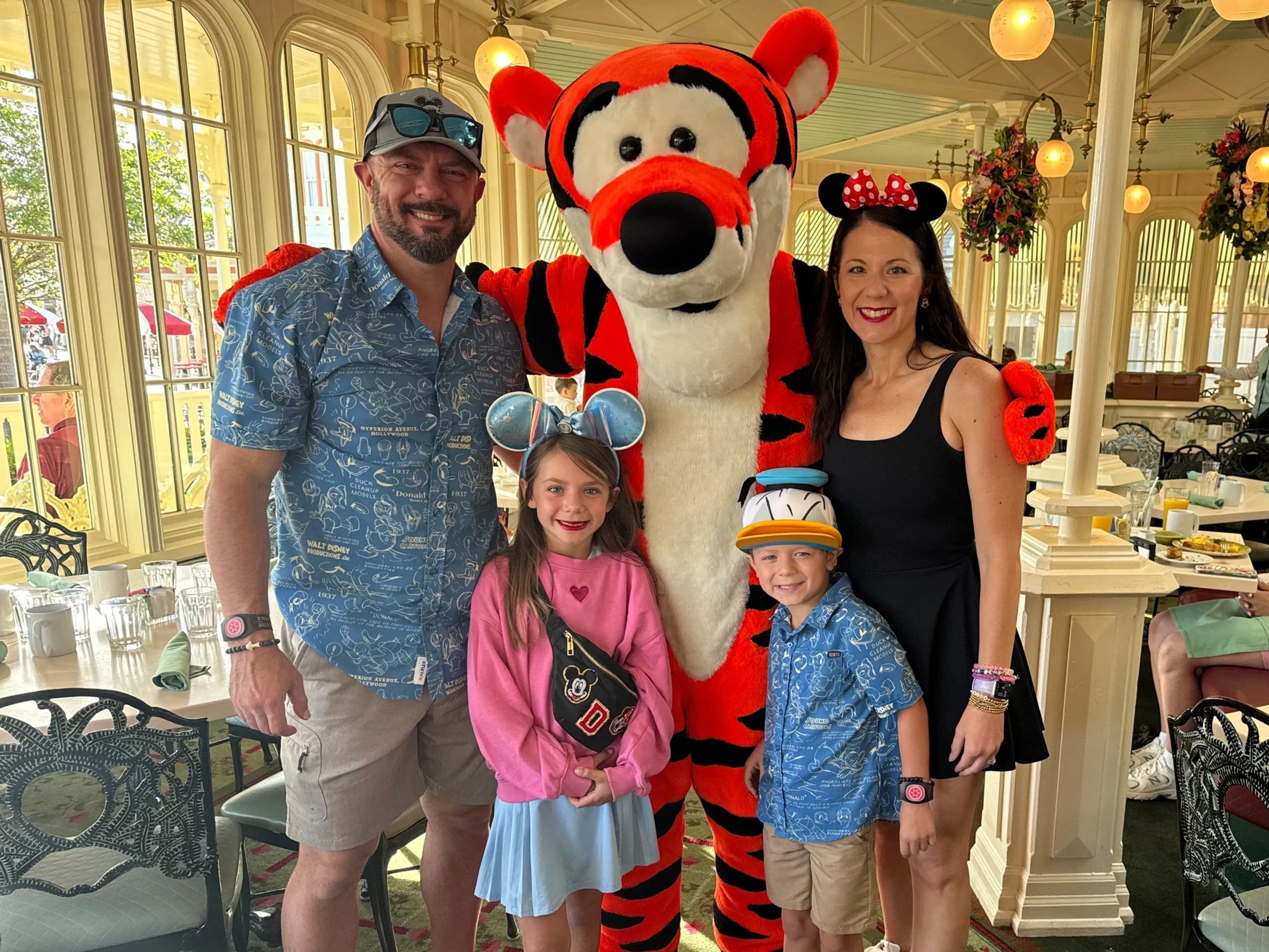 Family posing with Tigger at a Disney-themed restaurant.