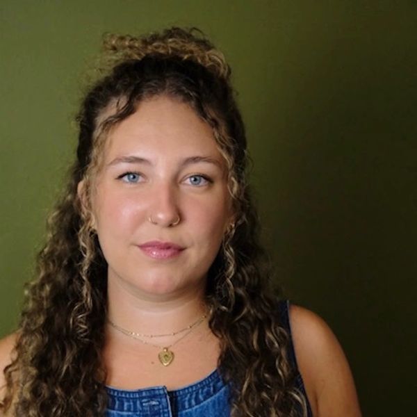 Woman with curly hair and blue eyes smiling softly.