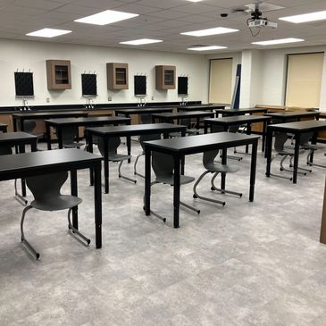 Empty classroom with black desks and chairs.