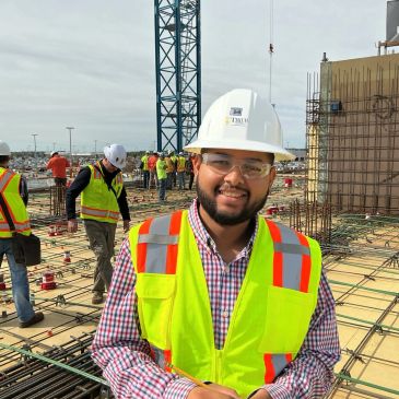 Smiling construction worker in safety gear at a building site.