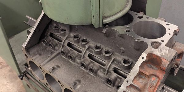 A metal engine block being machined on a vertical milling machine.
