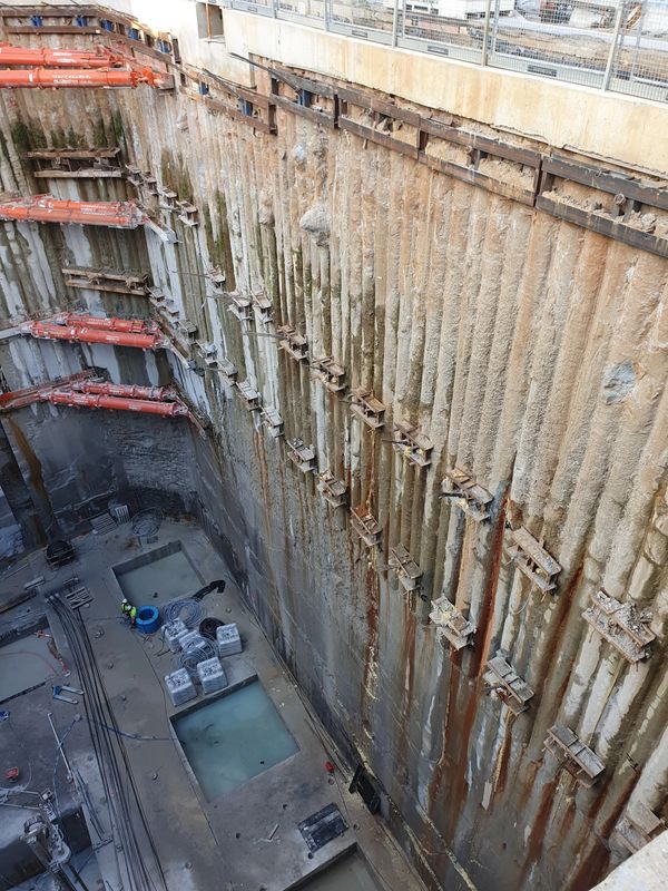 Deep construction excavation with worker and support beams.